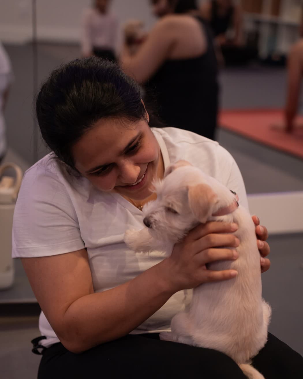 A student smiling as she cuddles a cream puppy on her mat